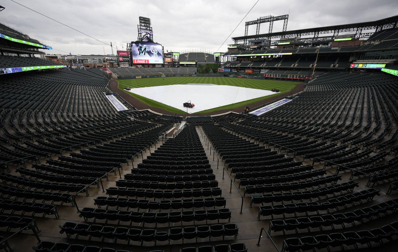 A tarpulin covers the diamond of Coors Field after a baseball game between the Miami Marlins and Co...