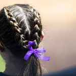 
              A Liberty softball player wears a purple ribbon in her hair during a game against Tennessee at Liberty Softball Stadium in Lynchburg, Va. on Wednesday, April 27, 2022  The ribbon is to honor James Madison University softball sophomore catcher Lauren Bernett who recently died. Griffin also shares the same jersey number as Bernett. (Kendall Warner/The News & Advance via AP)
            
