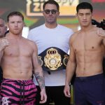 
              Canelo Alvarez, left, and Dmitry Bivol, right, pose next to promoter Eddie Hearn during a ceremonial weigh-in for their Saturday boxing fight, Friday, May 6, 2022, in Las Vegas. (AP Photo/John Locher)
            