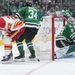 
              Calgary Flames center Trevor Lewis (22) and Dallas Stars right wing Denis Gurianov (34) look for the puck behind goaltender Jake Oettinger (29) in the second period of Game 4 of an NHL hockey Stanley Cup first-round playoff series, Monday, May 9, 2022, in Dallas. (AP Photo/Tony Gutierrez)
            