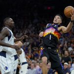
              Phoenix Suns guard Devin Booker (1) drives to the basket past Dallas Mavericks forward Dorian Finney-Smith, left, during the second half of Game 2 of an NBA basketball second-round playoff series, Wednesday, May 4, 2022, in Phoenix. (AP Photo/Matt York)
            