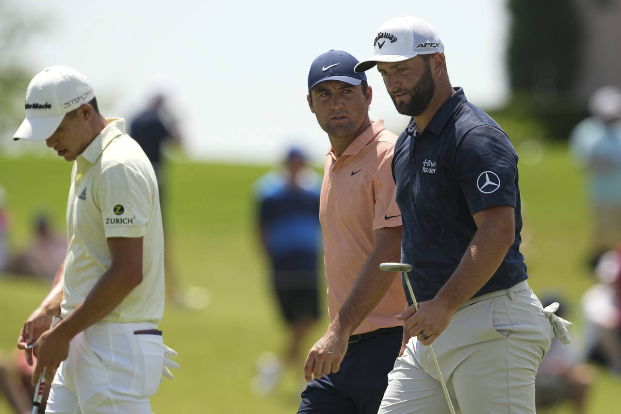 From right, Jon Rahm, of Spain, Scottie Scheffler and Collin Morikawa walk off the green on the fou...