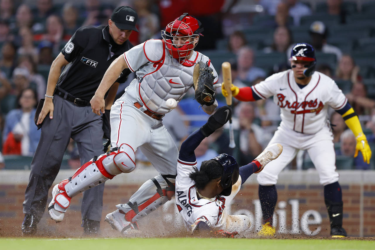 Atlanta Braves Ozzie Albies slides into home to score as the ball gets away from Philadelphia Phill...