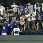 
              Fans try to catch ball hit by Kansas City Royals' MJ Melendez for a two-run home run during the eighth inning of a baseball game against the Chicago White Sox Wednesday, May 18, 2022, in Kansas City, Mo. (AP Photo/Charlie Riedel)
            