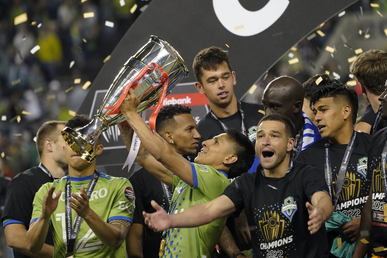 United States' Seattle Sounders forward Raul Ruidiaz holds the trophy alongside teammate midfielder...