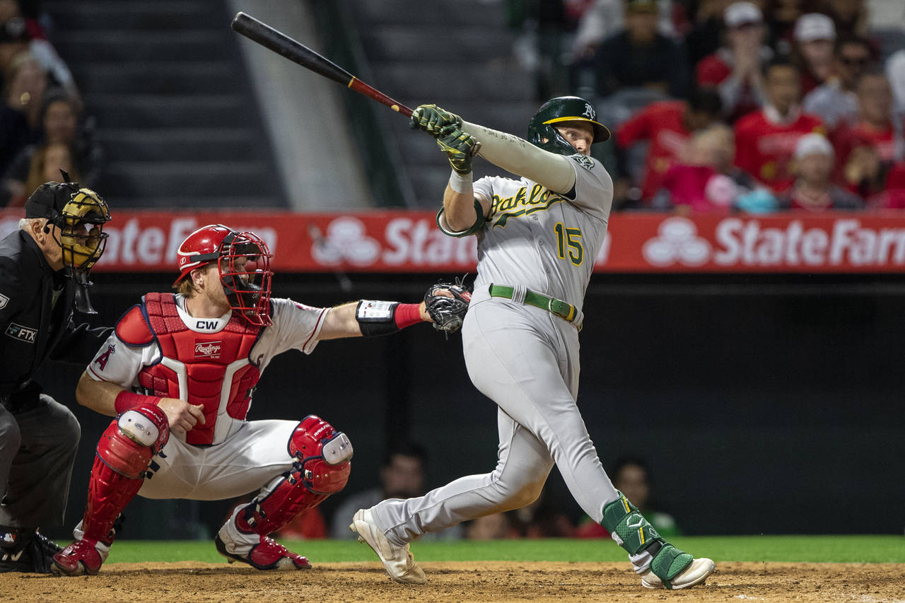 Oakland Athletics' Seth Brown follows through on a two-run home in front of Los Angeles Angels catc...