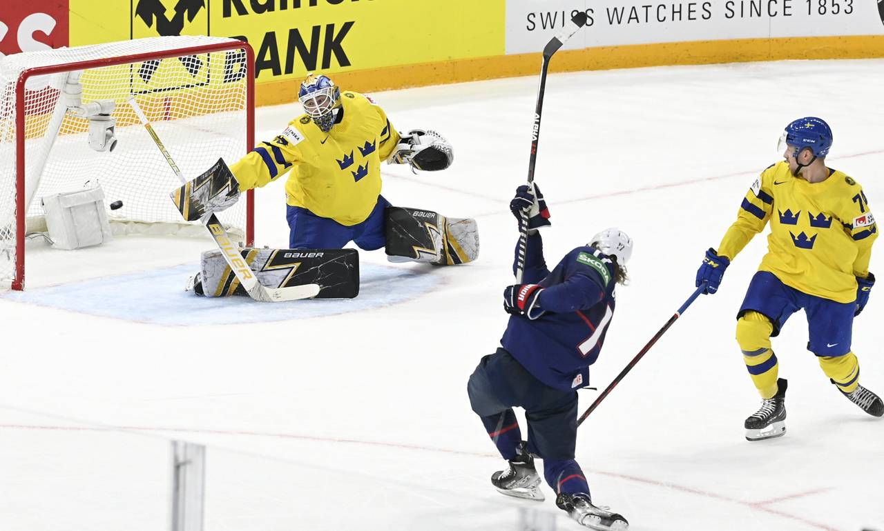 Adam Gaudette, center, of the United States of America scores the game-winning overtime goal past g...