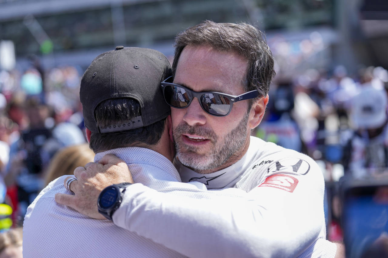 Driver Jimmie Johnson, right, gets a hug before the Indianapolis 500 auto race at Indianapolis Moto...