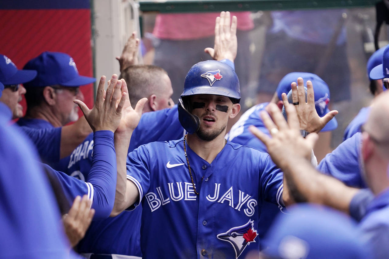 Toronto Blue Jays' Cavon Biggio is congratulated by teammates in the dugout after scoring on a doub...