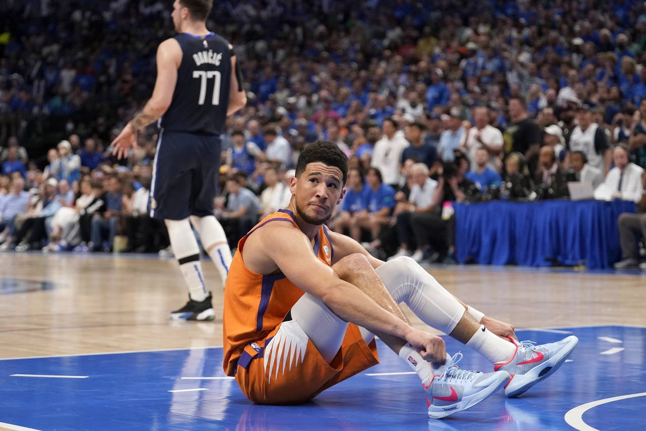 Phoenix Suns guard Devin Booker (1) looks up at an official standing nearby after being knocked to ...