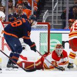 
              Calgary Flames goalie Jacob Markstrom, center, covers the puck as Edmonton Oilers winger Zach Hyman digs for it during the third period of Game 4 of an NHL hockey Stanley Cup playoffs second-round series Tuesday, May 24, 2022, in Edmonton, Alberta. (Jeff McIntosh/The Canadian Press via AP)
            