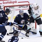 
              Winnipeg Jets' goaltender Eric Comrie (1) makes a save against Seattle Kraken's Jamie Oleksiak (24) as Jets' Dylan DeMelo (2) defends during the second period of NHL hockey game action in Winnipeg, Manitoba, Sunday, May 1, 2022. (Fred Greenslade/The Canadian Press via AP)
            