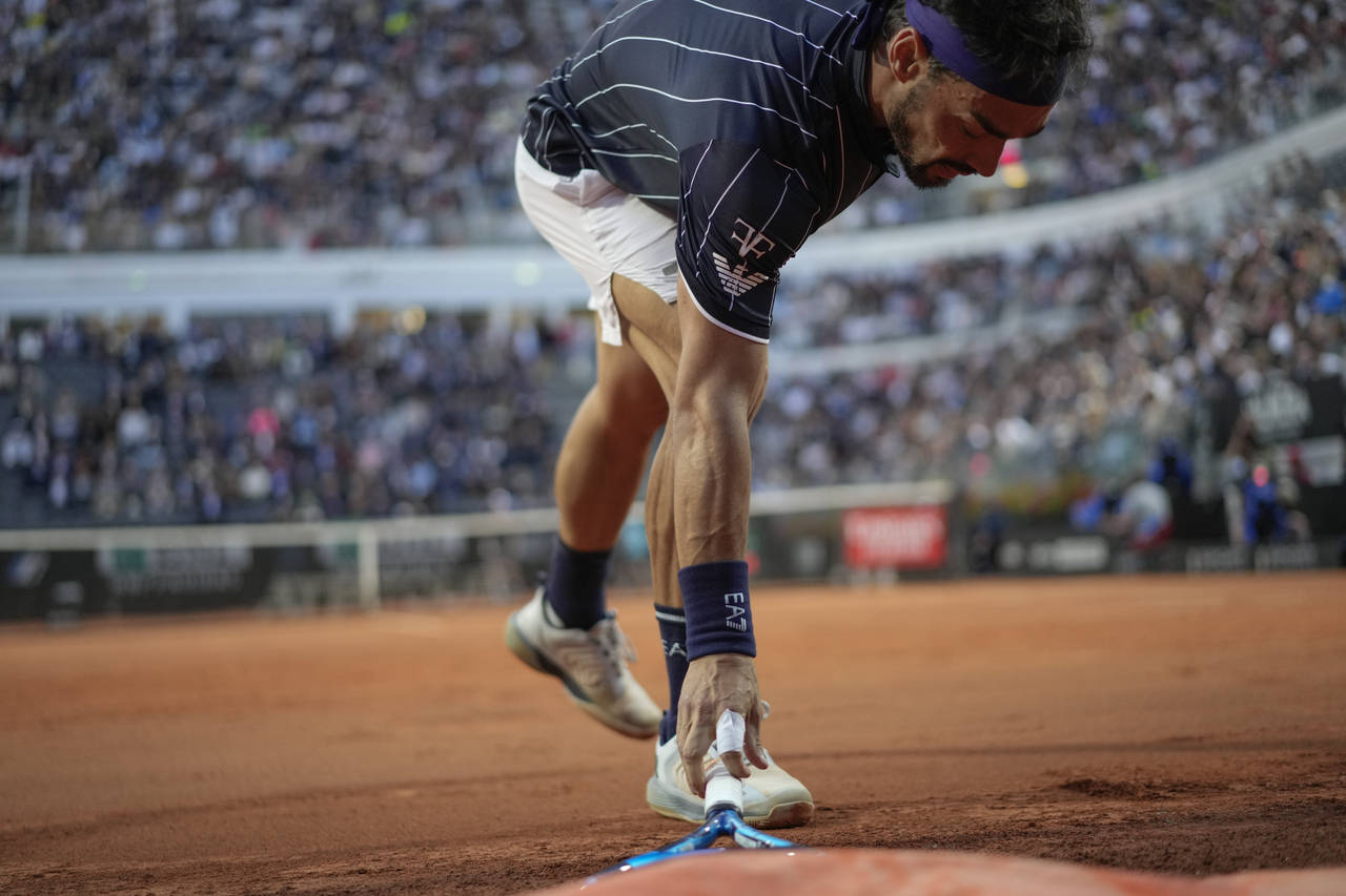 Fabio Fognini picks up his racket after throwing it to the ground during his match against Jannik S...