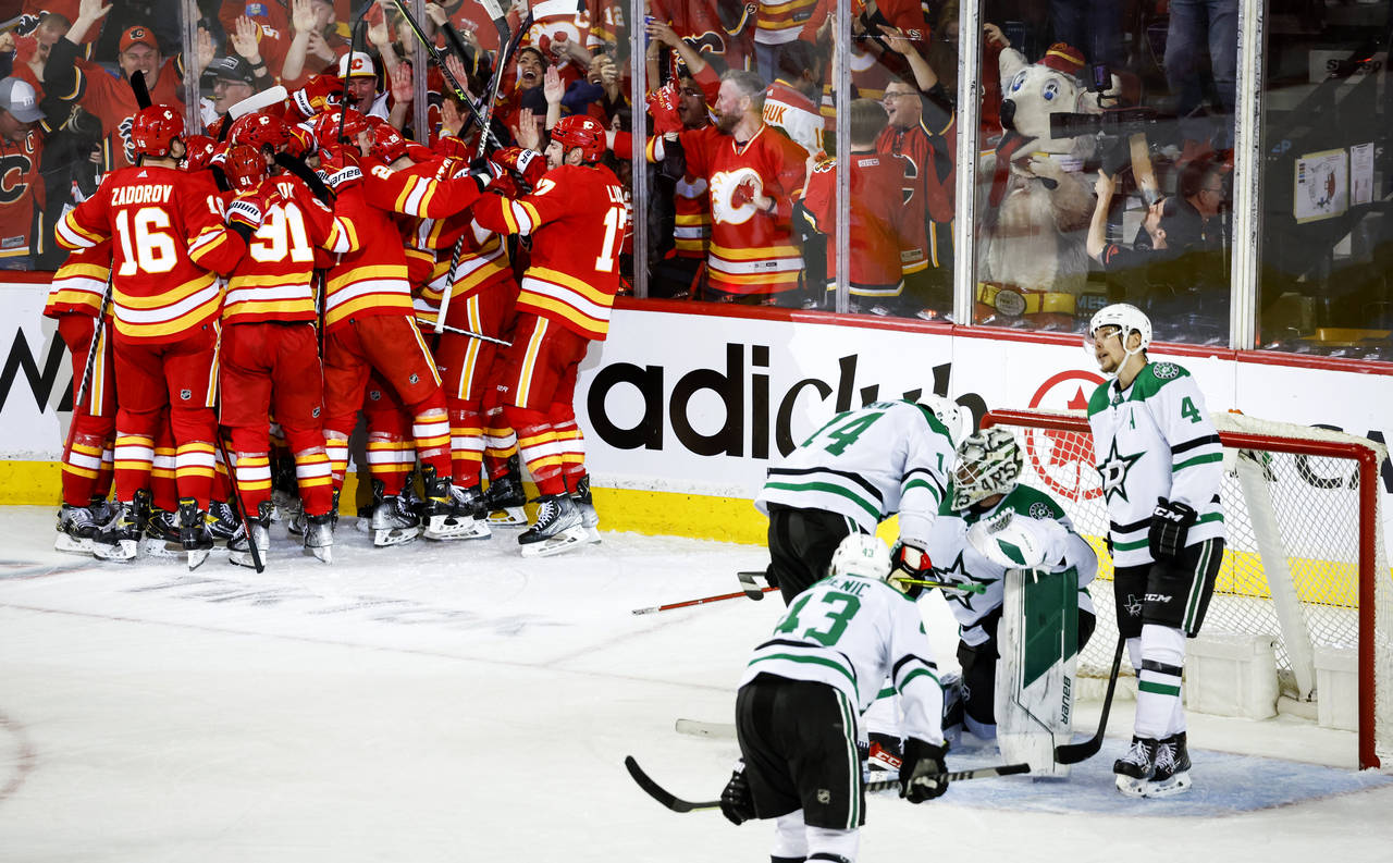 Dallas Stars goalie Jake Oettinger, second from right, is consoled by teammates as Calgary Flames c...
