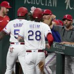 
              Texas Rangers' Jonah Heim (28) and Adolis Garcia, left, celebrate with manager Chris Woodward, right, and others after scoring on a Kole Calhoun single in the first inning of a baseball game against the Kansas City Royals, Tuesday, May 10, 2022, in Arlington, Texas. (AP Photo/Tony Gutierrez)
            