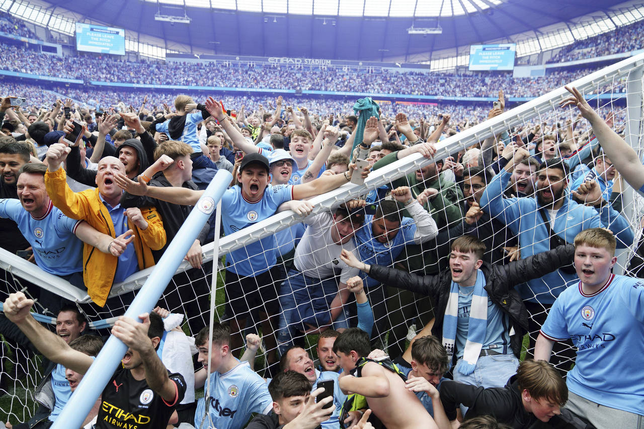 Manchester City fans invade the pitch after their side won the English Premier League following a 3...
