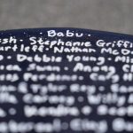 
              A surfboard belonging to Dan Fischer, of Newport, R.I., features the nickname of his late father "Babu," top, above the names of other families' lost loved ones, at Easton's Beach, in Newport, Wednesday, May 18, 2022. Fischer, 42, created the One Last Wave Project in January 2022 to use the healing power of the ocean to help families coping with a loss, as it helped him following the death of his father. Fischer places names onto his surfboards, then takes the surfboards out into the ocean as a way to memorialize the loved ones in a place that was meaningful to them. (AP Photo/Steven Senne)
            