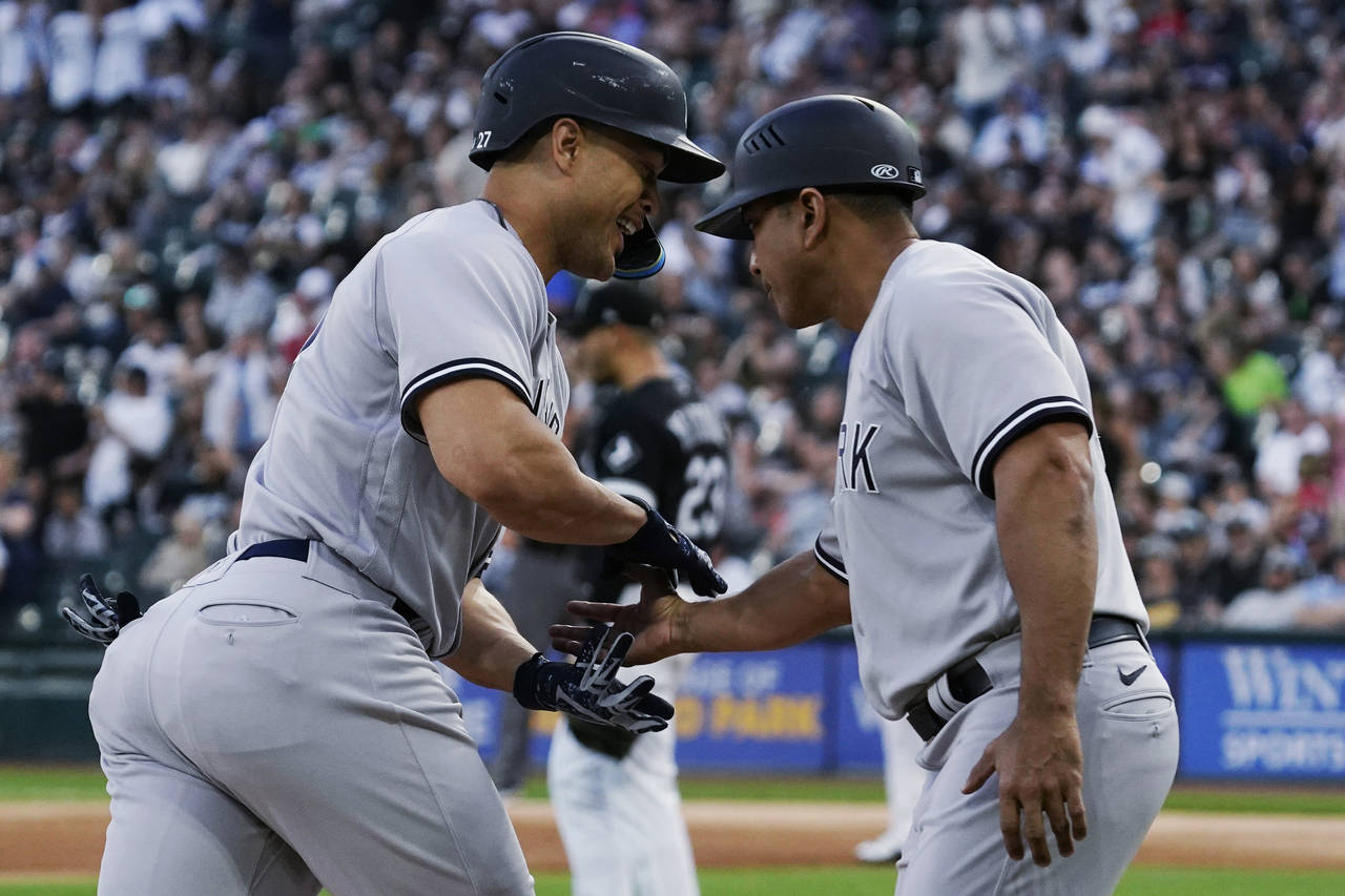 New York Yankees' Giancarlo Stanton, left, celebrates with third base coach Luis Rojas as he runs t...