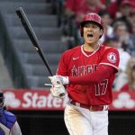 
              Los Angeles Angels' Shohei Ohtani, right, yells a warning after hitting a foul ball toward a camera well as Texas Rangers catcher Jonah Heim looks on during the third inning of a baseball game Wednesday, May 25, 2022, in Anaheim, Calif. (AP Photo/Mark J. Terrill)
            