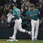 
              Seattle Mariners' Eugenio Suarez (28) celebrates with first base coach Kristopher Negron after hitting a two-run home run against the Tampa Bay Rays during the first inning of a baseball game Friday, May 6, 2022, in Seattle. (AP Photo/Jason Redmond)
            