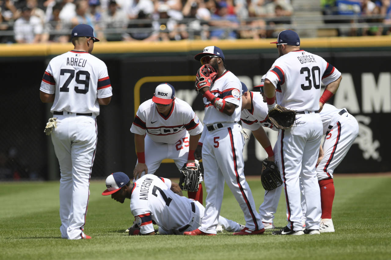 Chicago White Sox shortstop Tim Anderson lies on the field after being injured while throwing to fi...