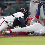 
              Philadelphia Phillies' Johan Camargo, right, beats the tag from Atlanta Braves catcher Travis d'Arnaud, left, to score on a two-run double by Roman Quinn in the third inning of a baseball game Monday, May 23, 2022, in Atlanta. (AP Photo/John Bazemore)
            