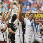 
              FILE - USA teammates Shannon Boxx, second from right, and Christie Rampone, far right, pose with the trophy as the USA team celebrates following their win over Japan at the FIFA Women's World Cup soccer championship in Vancouver, British Columbia, Canada, Sunday, July 5, 2015. Boxx showed that representation matters while also redefining the role of a defensive midfielder for the U.S. women's national team. Boxx made 195 appearances with the national team, most in the history of the team for a Black woman. she's been voted into the National Soccer Hall of Fame and will be enshrined next Friday, May 21, 2022, in Frisco, Texas. (Jonathan Hayward/The Canadian Press via AP, File)
            