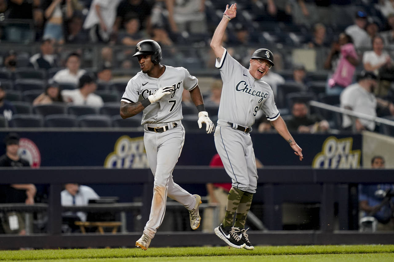 Chicago White Sox' Tim Anderson (7) celebrates with third base coach Joe McEwing (99) while running...