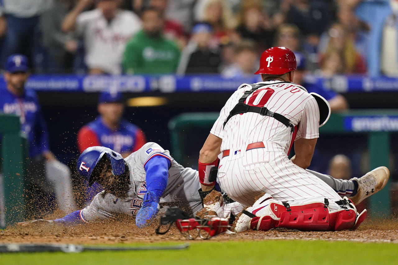 Texas Rangers' Adolis Garcia, left, is tagged out at home by Philadelphia Phillies catcher J.T. Rea...
