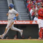 
              Texas Rangers' Marcus Semien, left, scores on a sacrifice fly hit by Mitch Garver as Los Angeles Angels catcher Kurt Suzuki stands at the plate during the first inning of a baseball game Wednesday, May 25, 2022, in Anaheim, Calif. (AP Photo/Mark J. Terrill)
            