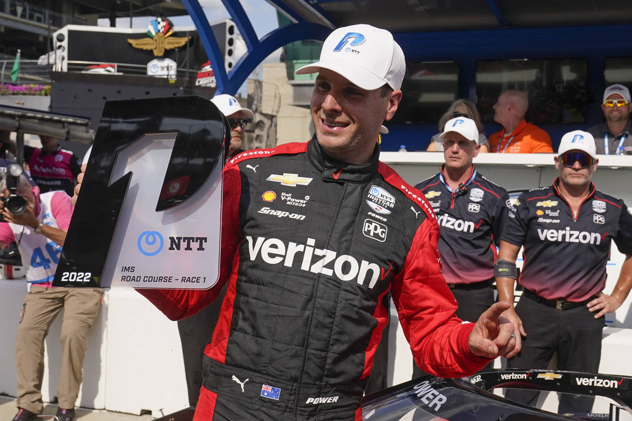 Will Power, of Australia, holds the trophy after winning the pole for the IndyCar auto race at Indi...
