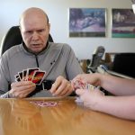 
              Former Detroit Red Wings star Vladimir Konstantinov plays Uno with health care provider Angela Martin, Tuesday, May 17, 2022, in West Bloomfield, Mich. Konstantinov is in danger of losing the 24/7 care he has had for two-plus decades. The disabled former NHL defenseman is a casualty of changes to Michigan's auto insurance law that curbed or cut what hospitals, residential care facilities and home providers can charge car insurers for care. Konstantinov suffered a severe brain stem injury from an accident in a limousine with an impaired driver after a Stanley Cup celebration nearly 25 years ago. (AP Photo/Carlos Osorio)
            