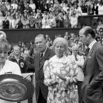 
              FILE - Chris Evert Lloyd admires her trophy, as the Duchess of Kent applauds, following the presentation ceremony on Wimbledon's Centre Court, Friday, July 3, 1981. Chris Evert appreciates that she, Serena Williams and other Wimbledon women's singles champions will now be listed on the All England Club's honor boards in a Centre Court hallway simply by their first initial and last name — the way the men's title winners always have been — instead of preceded by “Miss” or “Mrs.” (AP Photo/Bob Dear, File)
            