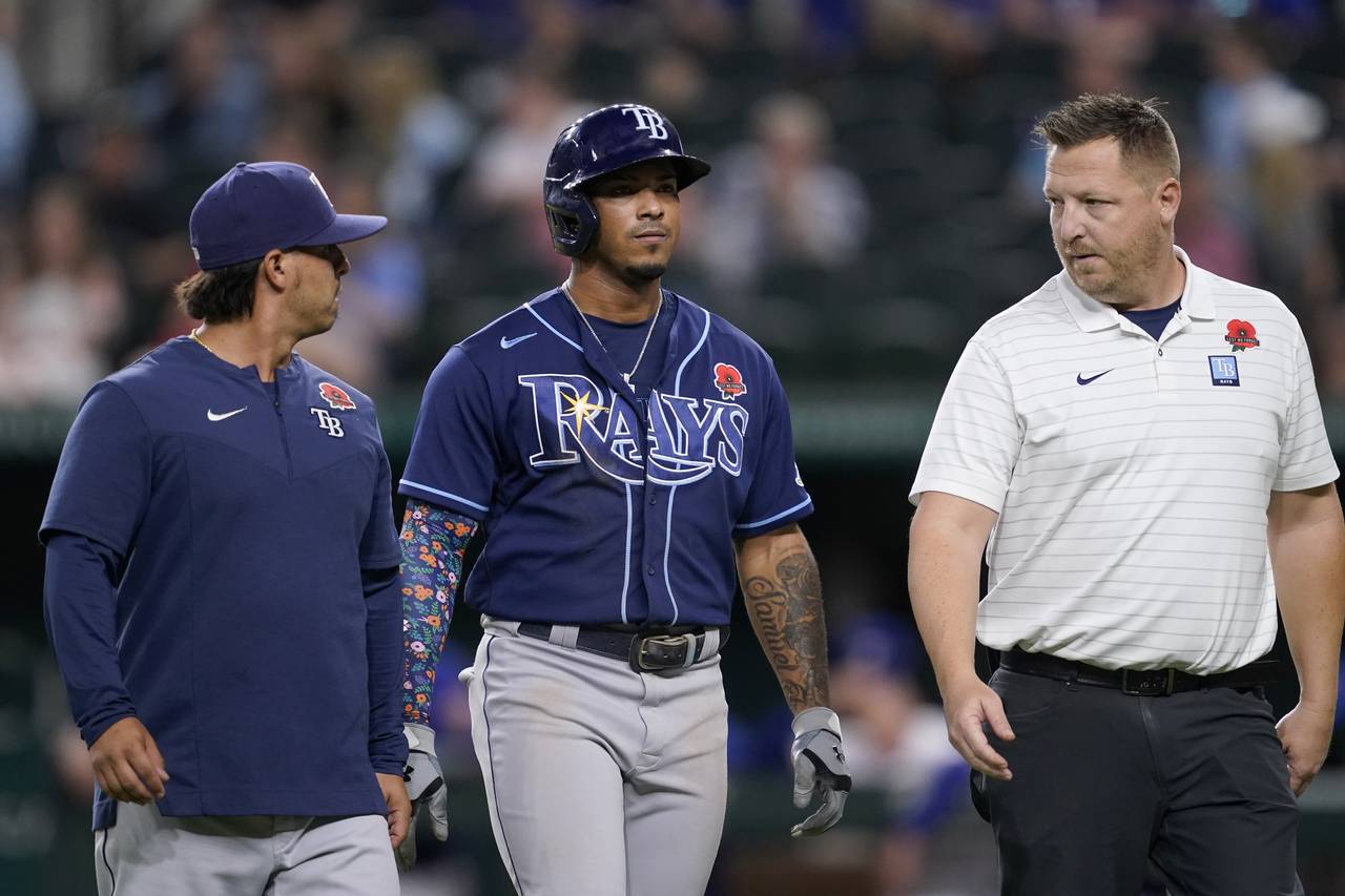 Tampa Bay Rays' Wander Franco, center, is escorted off the field by team staff after hitting a sing...