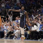 
              Phoenix Suns guard Devin Booker (1) stands by as Dallas Mavericks forward Dorian Finney-Smith (10) celebrates after sinking a 3-point basket in the first half of Game 4 of an NBA basketball second-round playoff series, Sunday, May 8, 2022, in Dallas. (AP Photo/Tony Gutierrez)
            