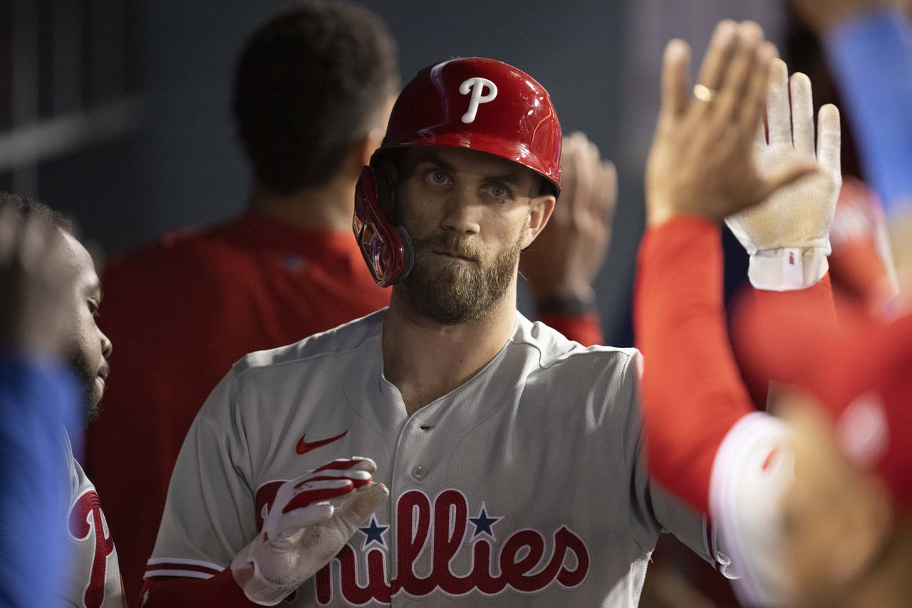 Philadelphia Phillies' Bryce Harper is greeted in the dugout after hitting an RBI sacrifice fly dur...