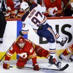 
              Edmonton Oilers center Connor McDavid (97) is checked by Calgary Flames forward Andrew Mangiapane during the first period of Game 2 of an NHL hockey Stanley Cup playoffs second-round series Friday, May 20, 2022, in Calgary, Alberta. (Jeff McIntosh/The Canadian Press via AP)
            
