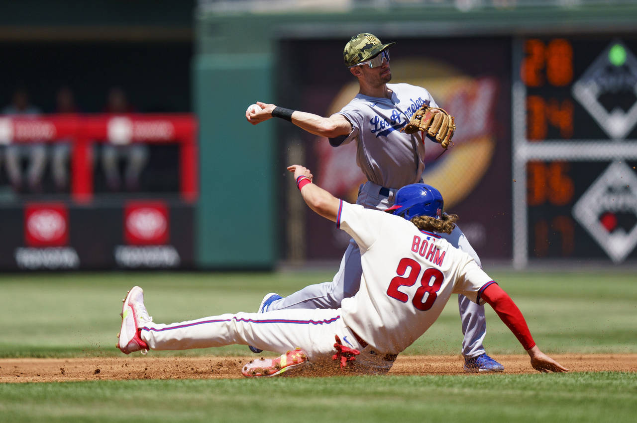 Los Angeles Dodgers shortstop Trea Turner, top, throws to first after getting an out against Philad...