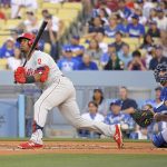 
              Philadelphia Phillies' Jean Segura, left, hits a three-run home run as Los Angeles Dodgers catcher Austin Barnes watches during the first inning of a baseball game Saturday, May 14, 2022, in Los Angeles. (AP Photo/Mark J. Terrill)
            