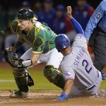 
              Texas Rangers' Marcus Semien (2) scores against Oakland Athletics catcher Sean Murphy during the eighth inning of a baseball game in Oakland, Calif., Friday, May 27, 2022. (AP Photo/Jeff Chiu)
            