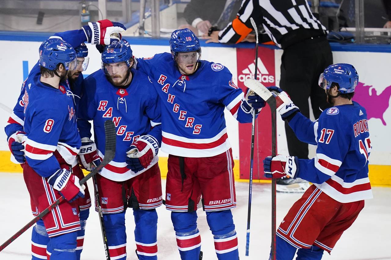 New York Rangers' Ryan Lindgren (55) celebrates an empty net goal with teammates Jacob Trouba (8), ...
