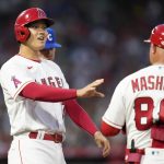 
              Los Angeles Angels designated hitter Shohei Ohtani, left, greets first base coach Damon Mashore (80) after walking to first during the fifth inning of a baseball game against the Kansas City Royals in Anaheim, Calif., Monday, June 20, 2022. (AP Photo/Ashley Landis)
            