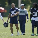 Amanda Ruller, left, who is currently working as an assistant running backs coach for the NFL football Seattle Seahawks through the league's Bill Walsh Diversity Fellowship program, walks with running backs Travis Homer (25), Seahawks run game coordinator and running backs coach Chad Morton, center, and DeeJay Dallas (31) during NFL football practice on May 31, 2022, in Renton, Wash. Ruller's job is scheduled to run through the Seahawks' second preseason game in August. (AP Photo/Ted S. Warren)