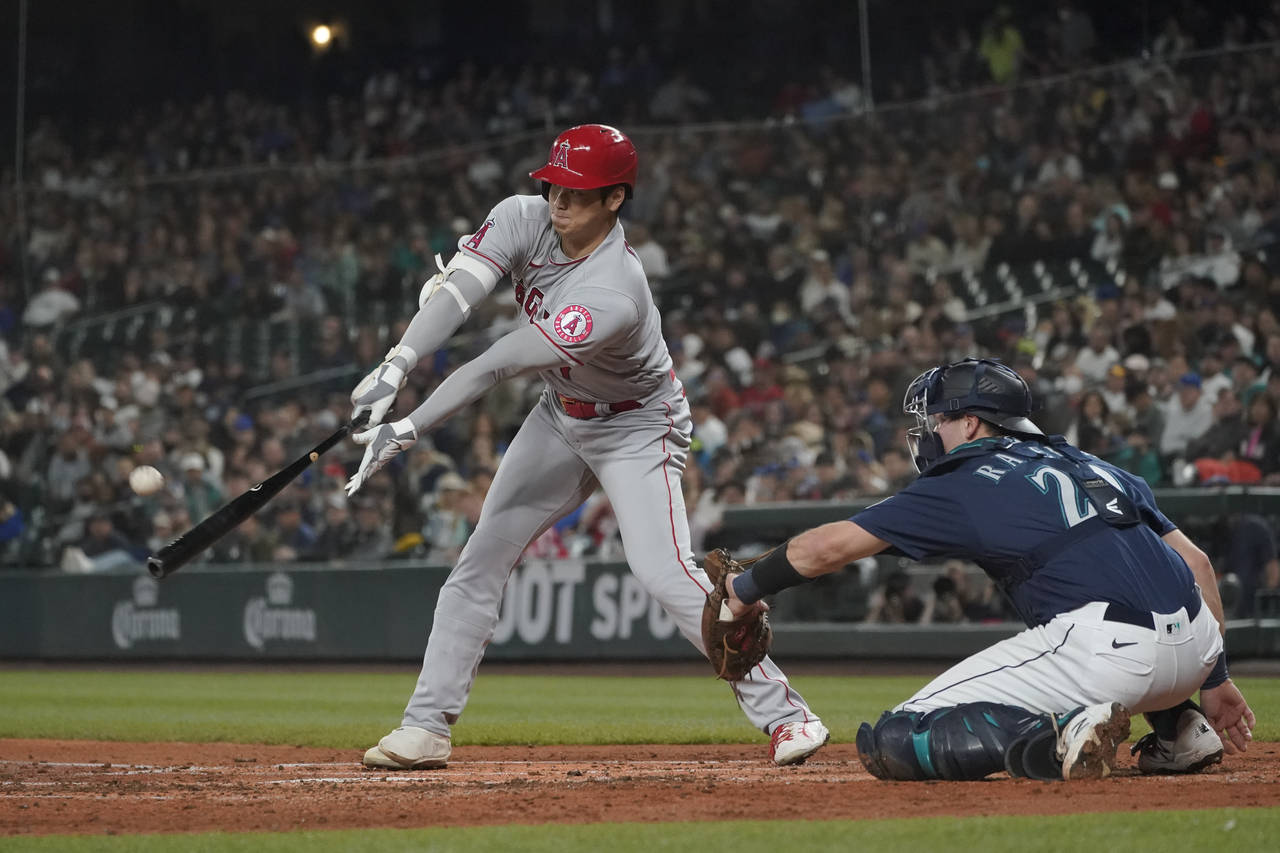 Los Angeles Angels' Shohei Ohtani flies out next to Seattle Mariners catcher Cal Raleigh during the...