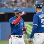
              Toronto Blue Jays' Santiago Espinal (5) celebrates with first base coach Mark Budzinski after hitting a single against the Boston Red Sox during the second inning of a baseball game Wednesday, June 29, 2022, in Toronto. (Christopher Katsarov/The Canadian Press via AP)
            
