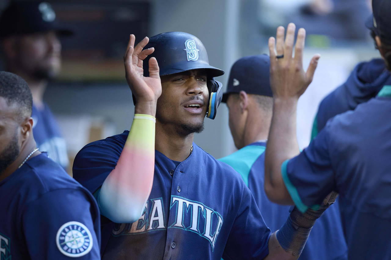Seattle Mariners' Julio Rodriguez is greeted in the dugout after scoring on a sacrifice hit by Abra...
