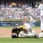 
              San Diego Padres' Manny Machado grips his left ankle after falling over first base while trying to beat out an infield hit to Colorado Rockies starting pitcher Antonio Senzatela in the first inning of a baseball game, Sunday, June 19, 2022, in Denver. Machado was helped off the field and was called out on the play. (AP Photo/David Zalubowski)
            