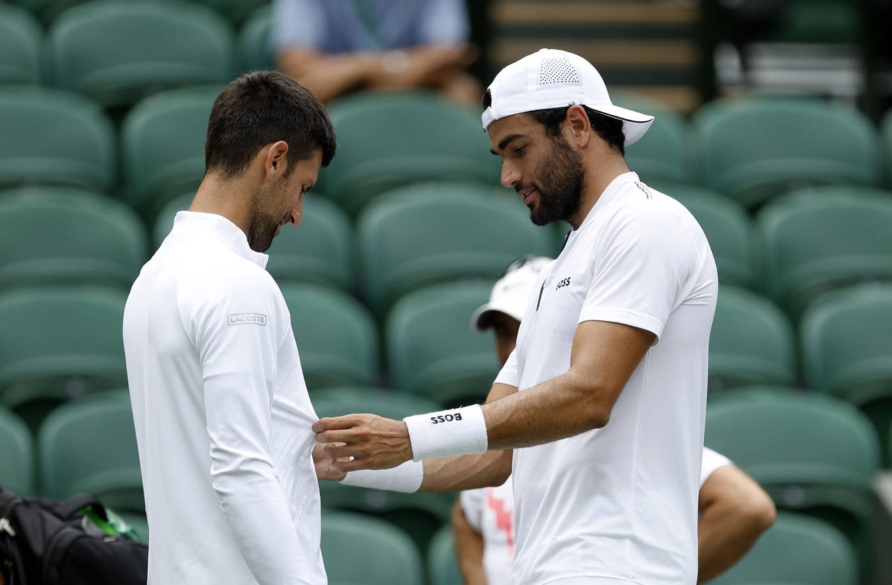 Italy's Matteo Berrettini checks out the clothing worn by Serbia's Novak Djokovic on centre court a...