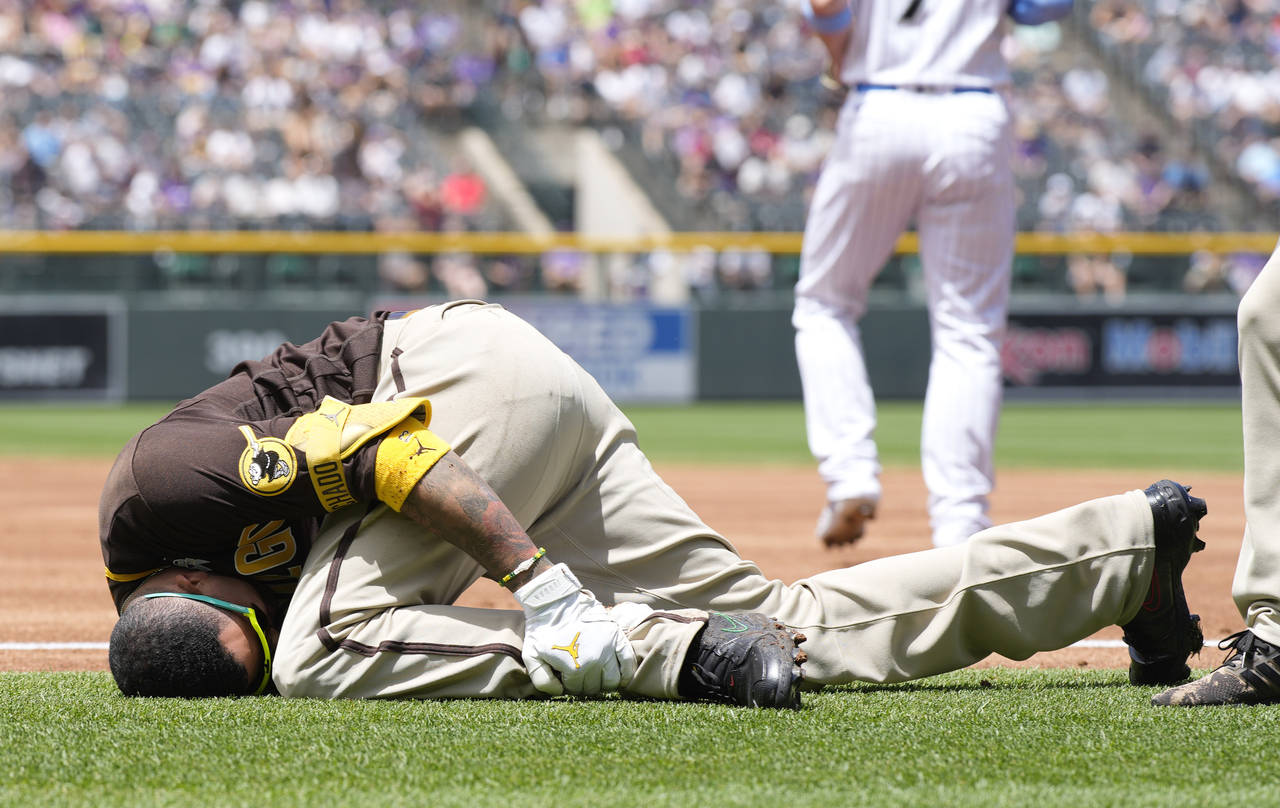 San Diego Padres' Manny Machado grabs his left ankle after being injured while trying to run out a ...