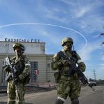 
              Russian troops guard an entrance of the Kakhovka Hydroelectric Station, a run-of-the-river power plant on the Dnieper River in Kherson region, southern Ukraine, Friday, May 20, 2022, during a trip organized by the Russian Ministry of Defense. The Kherson region has been under control of the Russian forces since the early days of the Russian military action in Ukraine. (AP Photo)
            